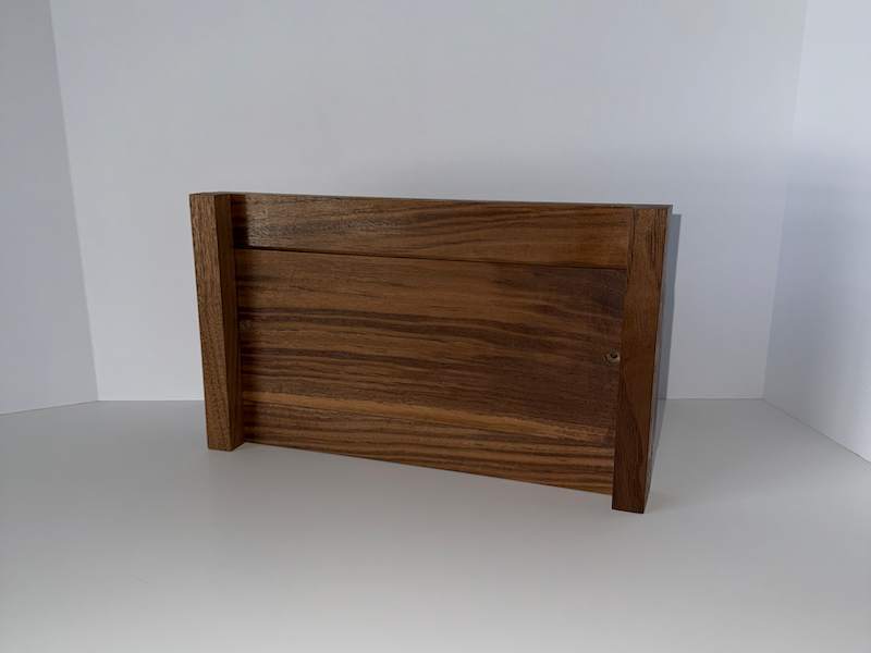 Wooden walnut snowboard rack against a white wall